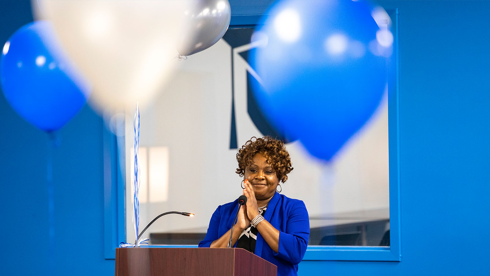 Woman stands at podium with hands together