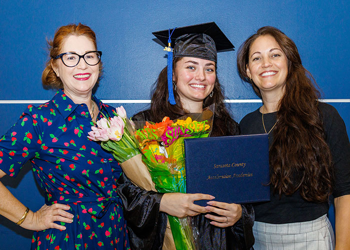High school graduates stands with two women